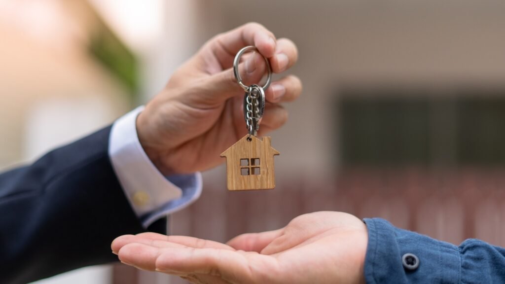 mão de homem de terno entrega chave de casa para mão de homem de blusa de manga azul
