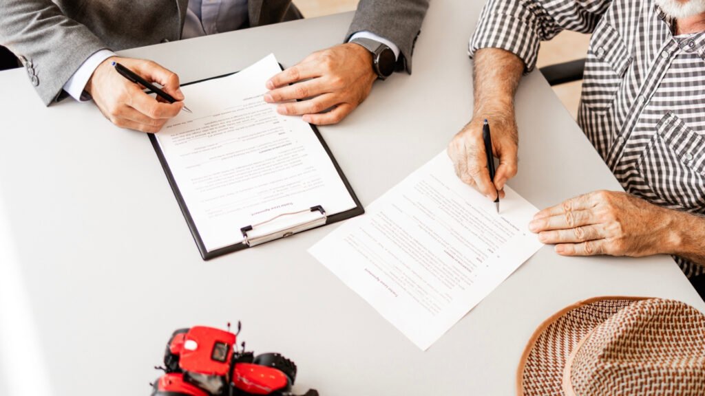 duas pessoas assinam papéis em uma mesa