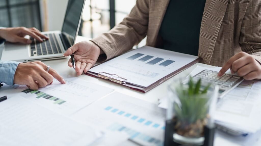 pessoas estão em mesa e trabalham com papés e notebook