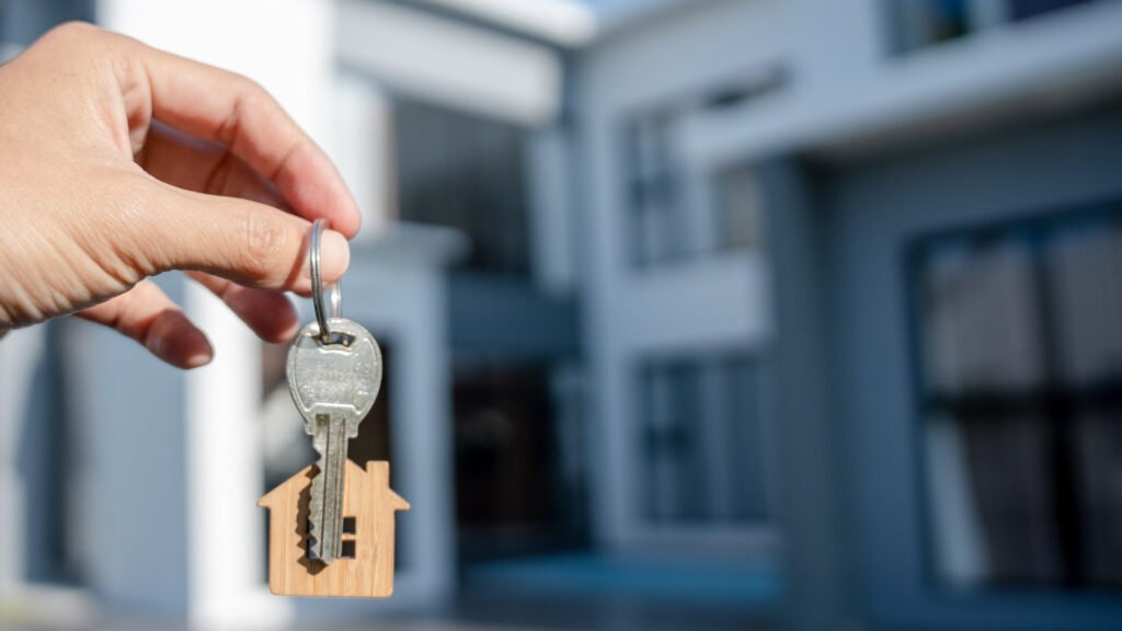 mãos seguram chave em frente de casa